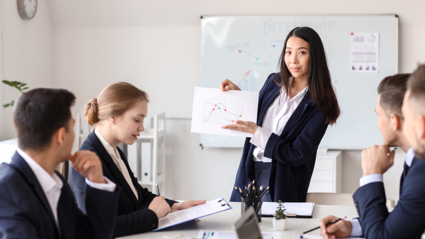 A professional presenting a chart to her team during a business strategy meeting.
