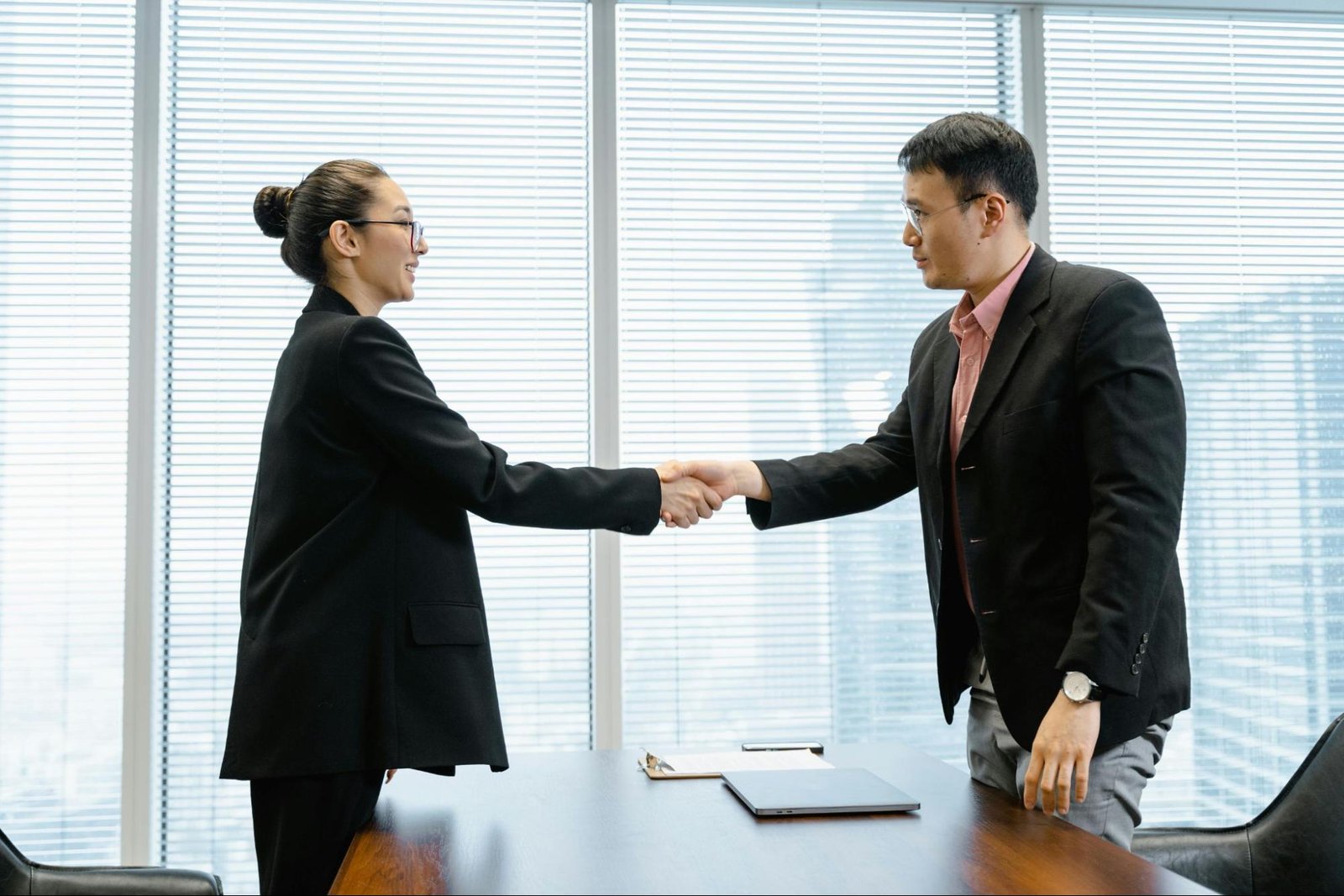 Two professionals shaking hands after coming to an agreement on a contract.