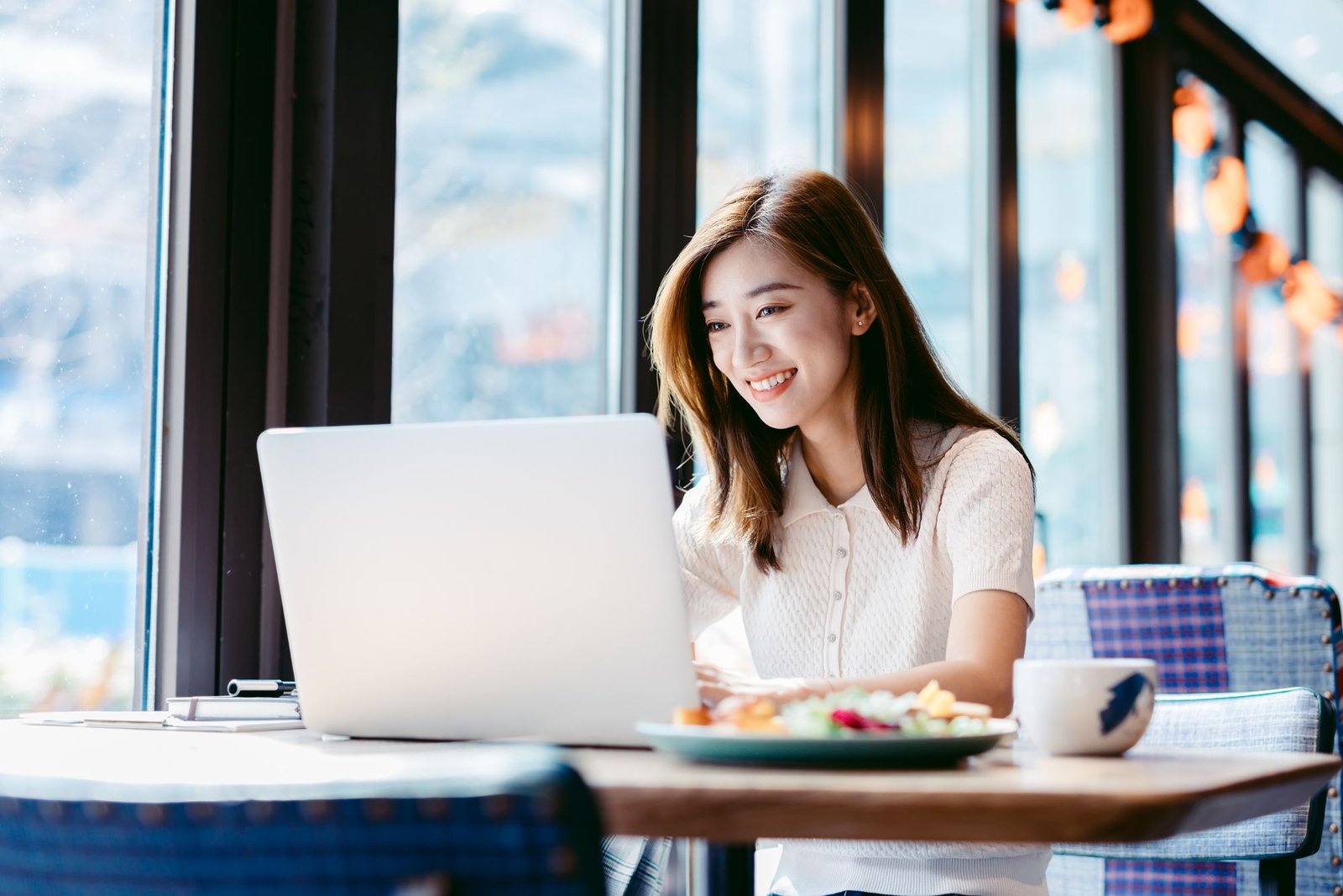 A woman using her laptop at a cafe, exploring SkillsFuture Credit courses online.