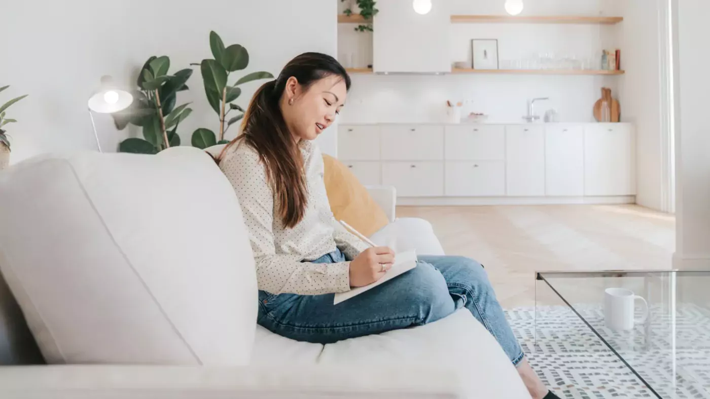 Young woman writing in a notebook while working from home