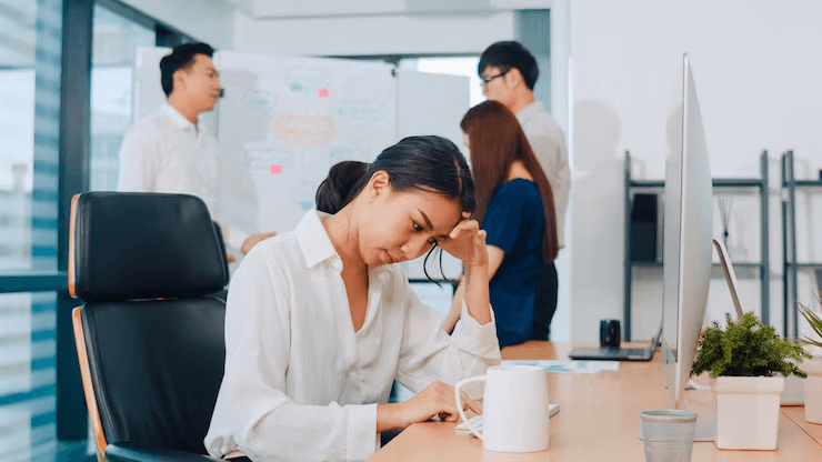 An office worker looks tired and frustrated as they work