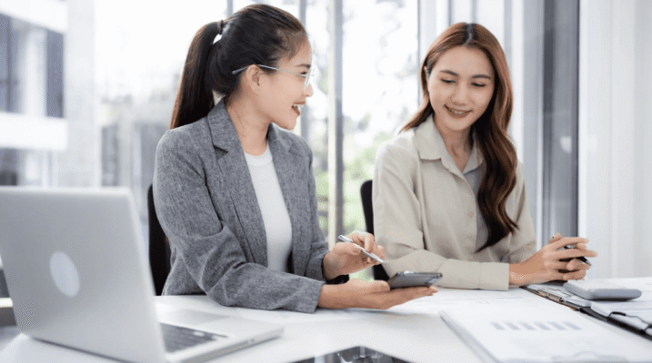 Two HR professionals in a Singapore office reviewing recruitment metrics—2025 hiring lessons Singapore and plans for 2026.